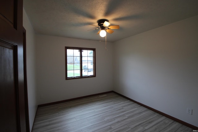 empty room featuring a textured ceiling, light hardwood / wood-style flooring, and ceiling fan