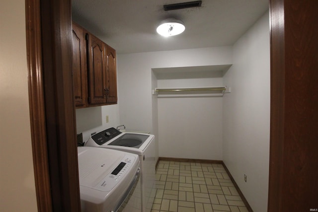 clothes washing area featuring cabinets and independent washer and dryer