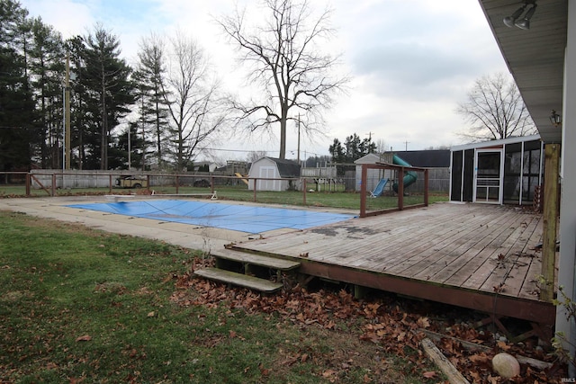 view of swimming pool featuring a playground, a fenced backyard, a sunroom, a lawn, and a fenced in pool