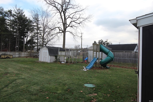 view of jungle gym featuring an outbuilding, a fenced backyard, a yard, and a storage shed