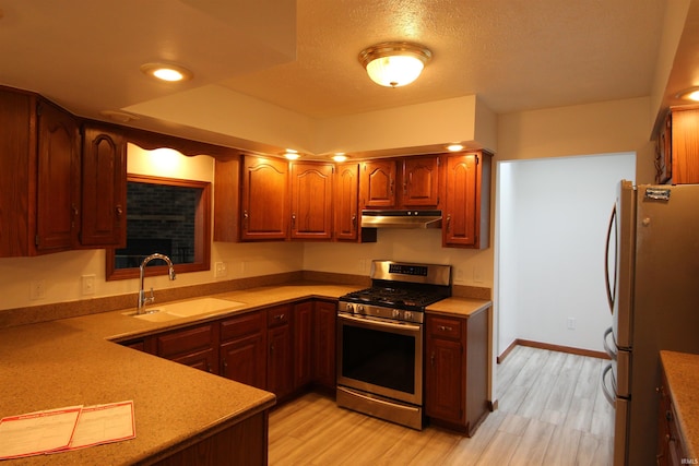 kitchen featuring sink, stainless steel appliances, a textured ceiling, and light hardwood / wood-style flooring