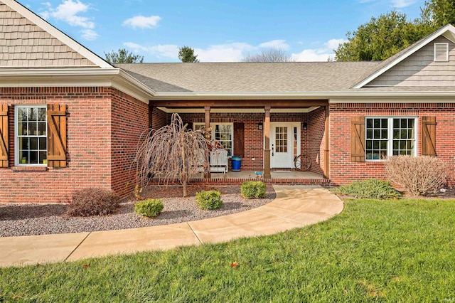 doorway to property featuring covered porch and a lawn