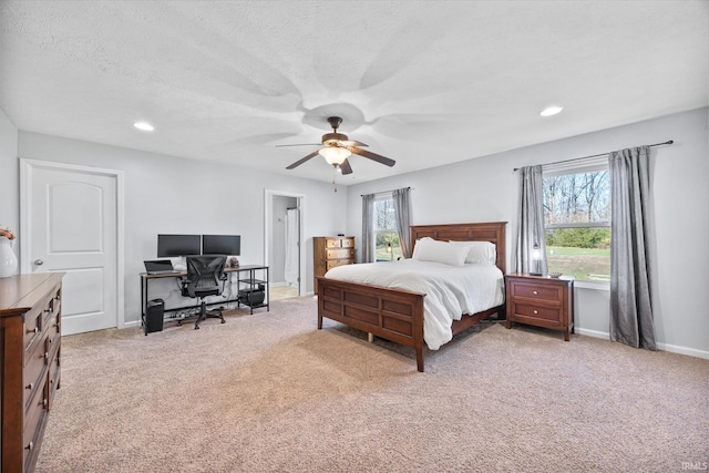 bedroom featuring a textured ceiling, light colored carpet, and ceiling fan