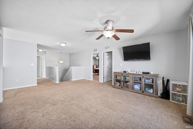 living room featuring ceiling fan, carpet floors, and a textured ceiling