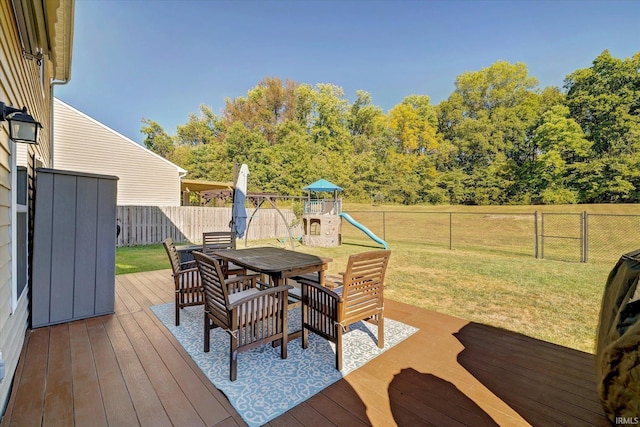 wooden deck with a playground and a yard