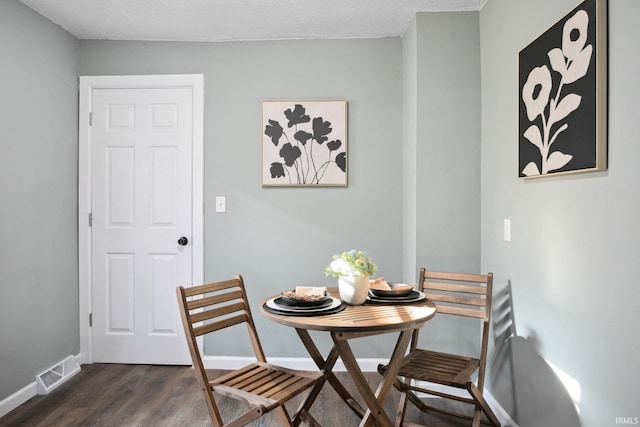 dining area with dark wood-type flooring and a textured ceiling