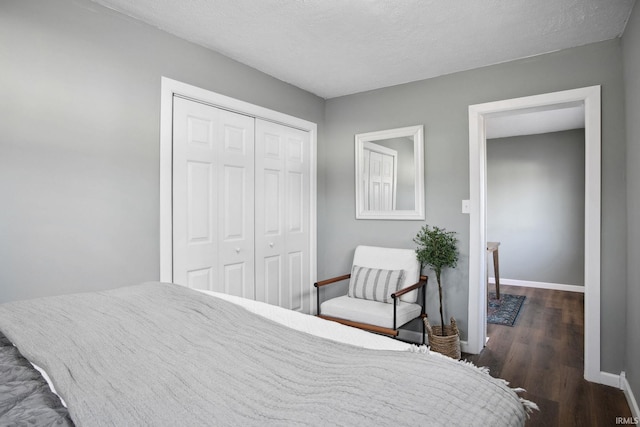 bedroom with a textured ceiling, dark hardwood / wood-style floors, and a closet