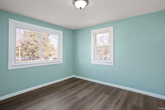 empty room featuring a textured ceiling, a wealth of natural light, and dark hardwood / wood-style floors