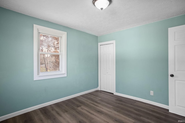 unfurnished bedroom featuring a textured ceiling and dark wood-type flooring