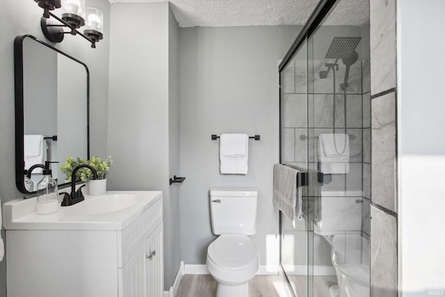 bathroom featuring an enclosed shower, vanity, a textured ceiling, wood-type flooring, and toilet