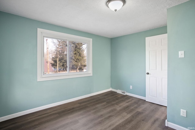 spare room with a textured ceiling and dark hardwood / wood-style floors