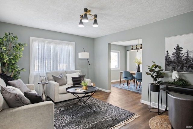 living room featuring dark hardwood / wood-style flooring, a textured ceiling, and an inviting chandelier