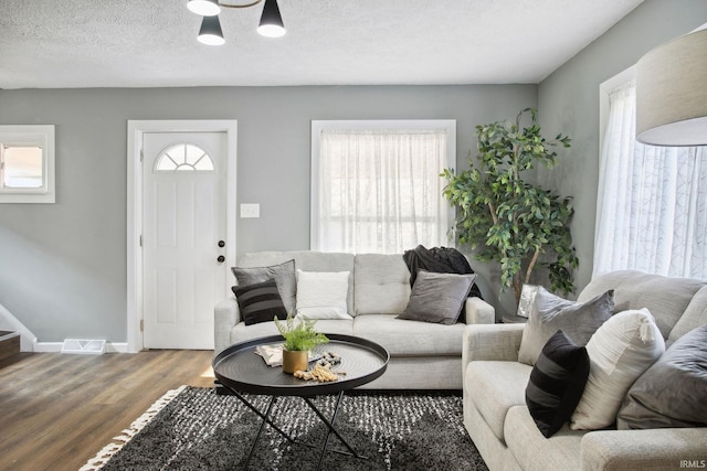 living room featuring dark hardwood / wood-style flooring, a healthy amount of sunlight, and a textured ceiling