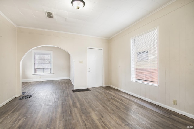 spare room featuring dark wood-type flooring, a healthy amount of sunlight, and ornamental molding