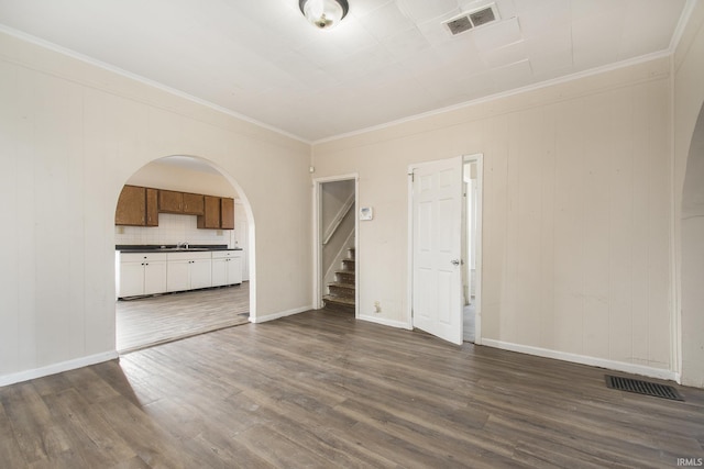 unfurnished living room featuring sink, dark hardwood / wood-style flooring, and ornamental molding