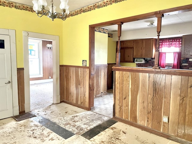 kitchen featuring kitchen peninsula, wooden walls, hanging light fixtures, and an inviting chandelier