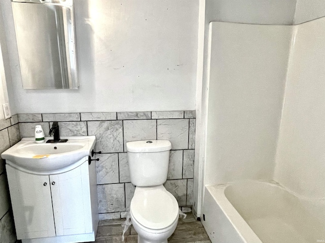 bathroom featuring vanity, toilet, and tile walls