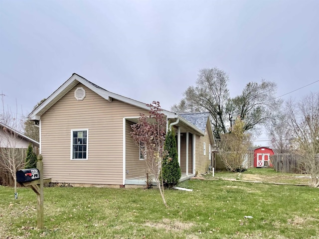 back of house with a yard and a shed