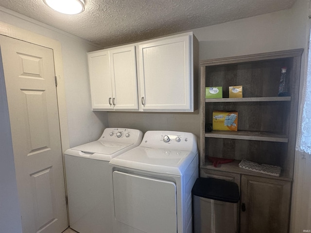 laundry room with washing machine and dryer, cabinets, and a textured ceiling