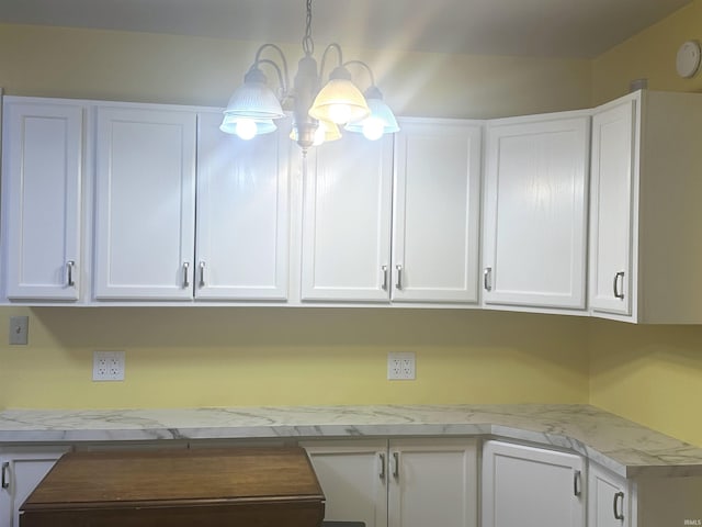 interior space featuring white cabinets, decorative light fixtures, and a notable chandelier