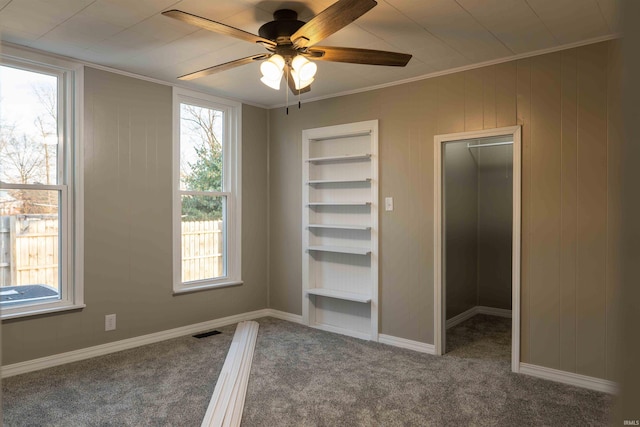 unfurnished bedroom featuring ceiling fan, carpet floors, crown molding, and multiple windows