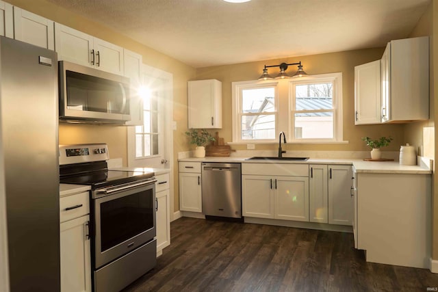 kitchen featuring white cabinetry, sink, dark wood-type flooring, a textured ceiling, and appliances with stainless steel finishes