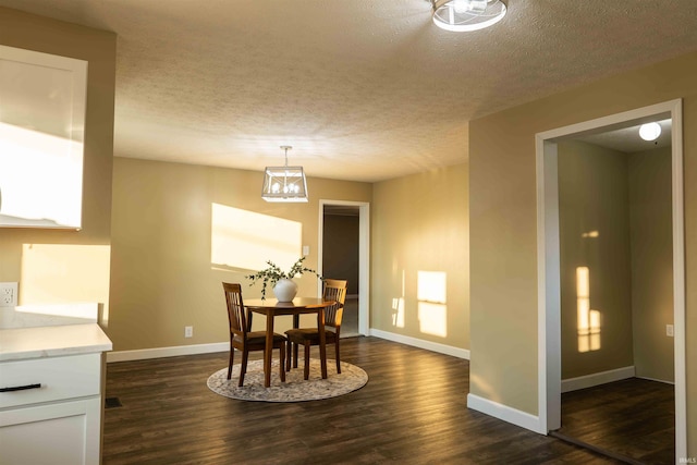 dining area with dark hardwood / wood-style flooring, a textured ceiling, and a chandelier