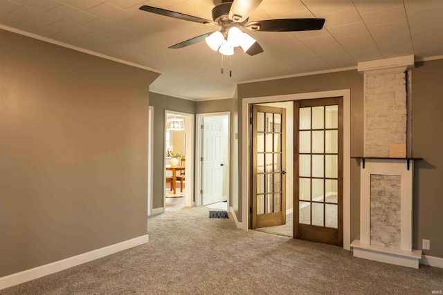 carpeted empty room featuring ceiling fan, decorative columns, ornamental molding, and french doors