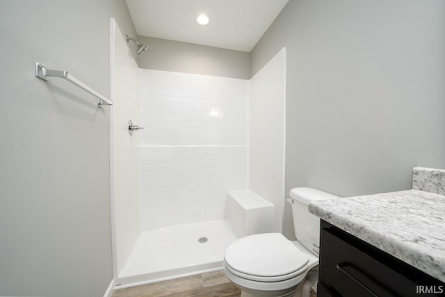 bathroom with hardwood / wood-style flooring, vanity, toilet, and a shower