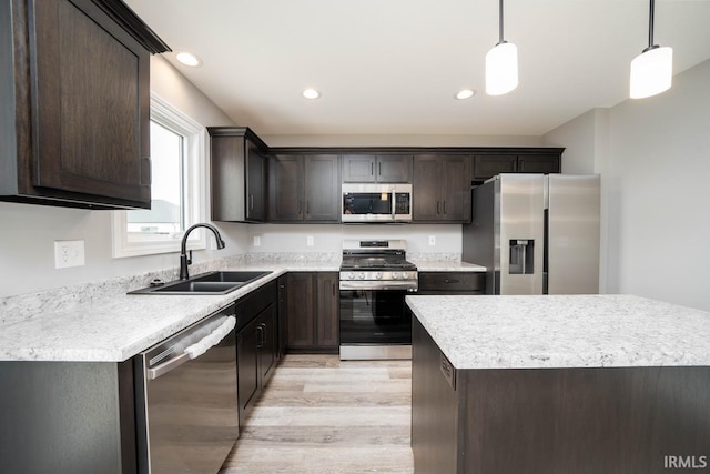 kitchen featuring pendant lighting, sink, appliances with stainless steel finishes, dark brown cabinets, and light hardwood / wood-style floors