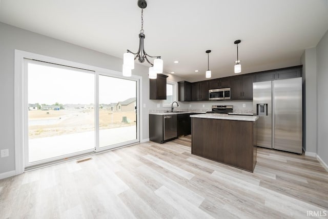 kitchen featuring sink, stainless steel appliances, pendant lighting, dark brown cabinets, and light wood-type flooring