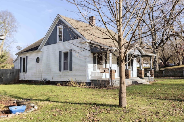 rear view of house featuring covered porch and a lawn