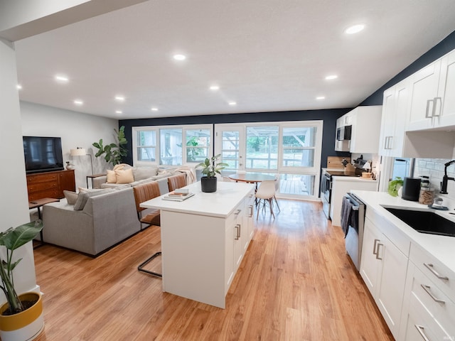 kitchen featuring white cabinets, appliances with stainless steel finishes, a kitchen island, and a healthy amount of sunlight