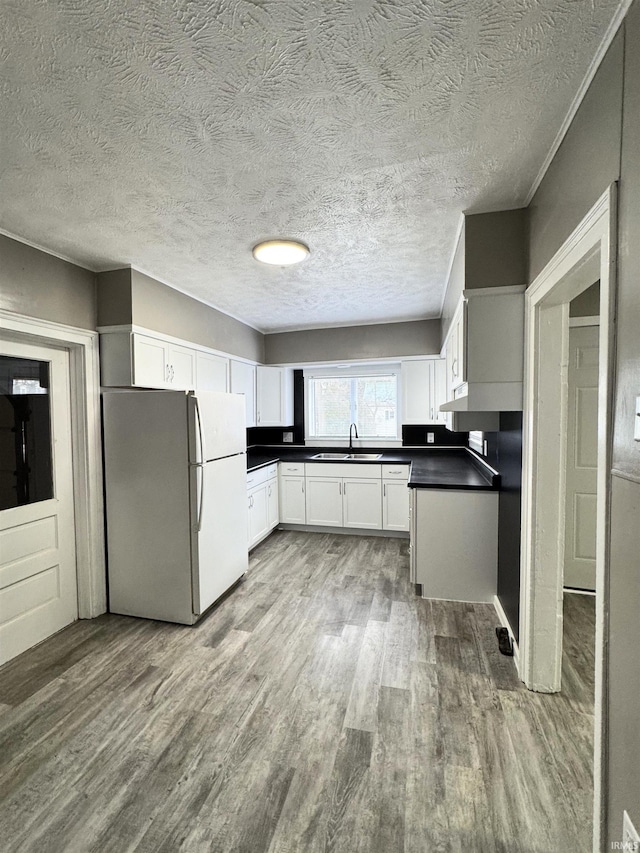 kitchen featuring white cabinetry, sink, white fridge, a textured ceiling, and light wood-type flooring