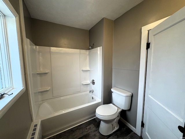 bathroom with shower / bathing tub combination, wood-type flooring, a textured ceiling, and toilet