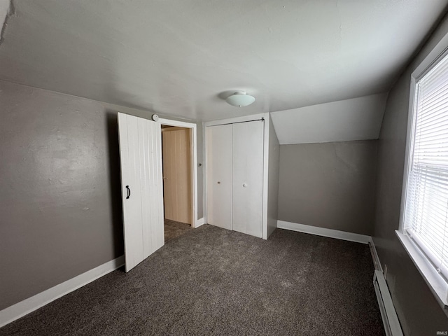 bonus room with dark colored carpet, a healthy amount of sunlight, baseboard heating, and vaulted ceiling