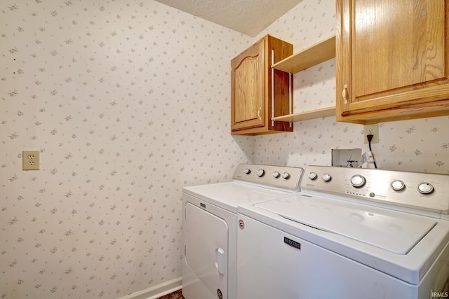 clothes washing area featuring cabinets, a textured ceiling, and washer and clothes dryer