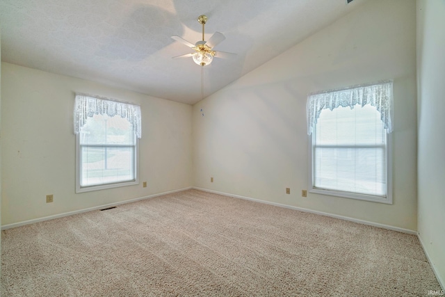 empty room with a wealth of natural light, ceiling fan, light colored carpet, and lofted ceiling