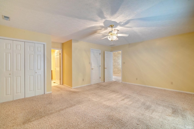 unfurnished bedroom featuring light carpet, a textured ceiling, and ceiling fan