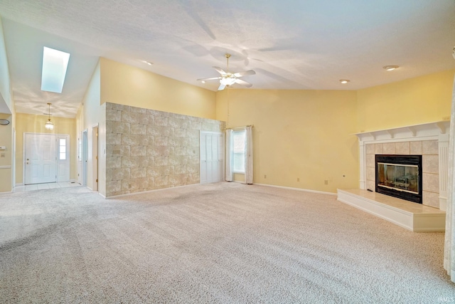 unfurnished living room featuring carpet floors, high vaulted ceiling, and a tiled fireplace