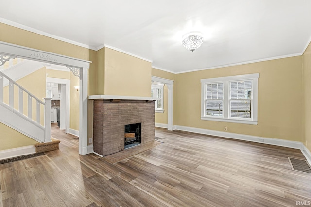 unfurnished living room featuring wood-type flooring, ornamental molding, and a brick fireplace