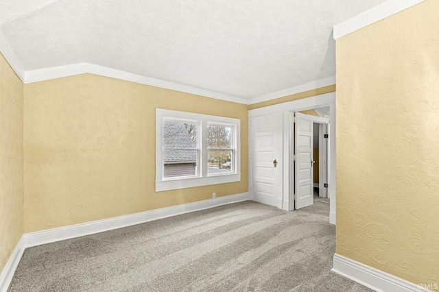 carpeted spare room with lofted ceiling, a textured ceiling, and crown molding