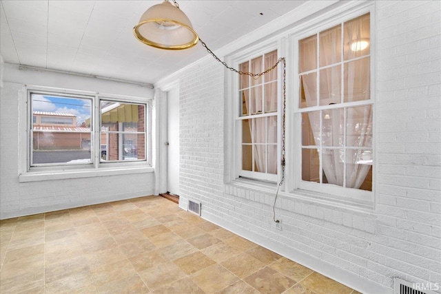 empty room featuring ornamental molding and brick wall