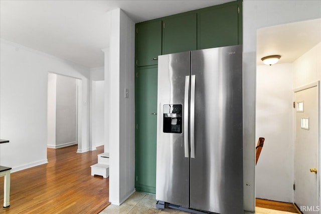 kitchen with stainless steel refrigerator with ice dispenser, light wood-type flooring, and green cabinets