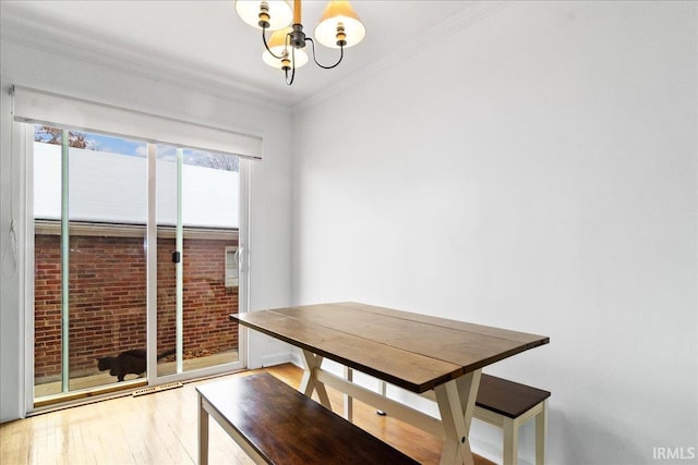 unfurnished dining area featuring light wood-type flooring, crown molding, and a notable chandelier