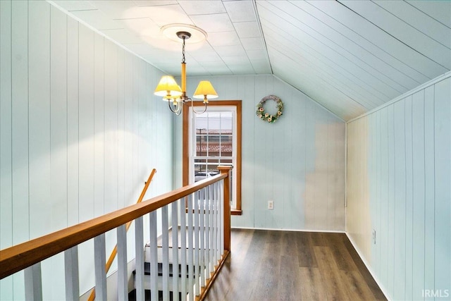 hall featuring wood walls, dark hardwood / wood-style flooring, lofted ceiling, and an inviting chandelier