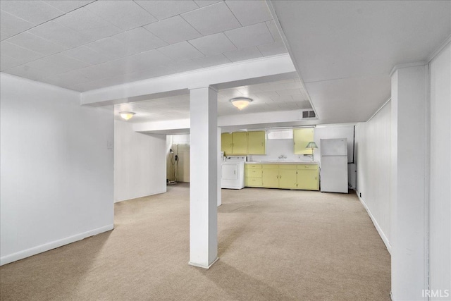 basement with light carpet, washer / dryer, white fridge, and ornamental molding