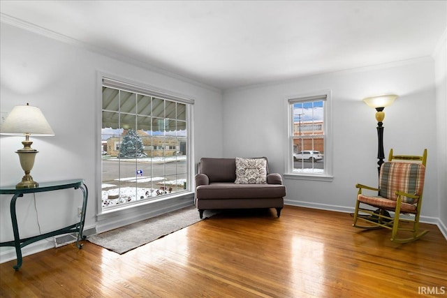 sitting room with a wealth of natural light, wood-type flooring, and ornamental molding