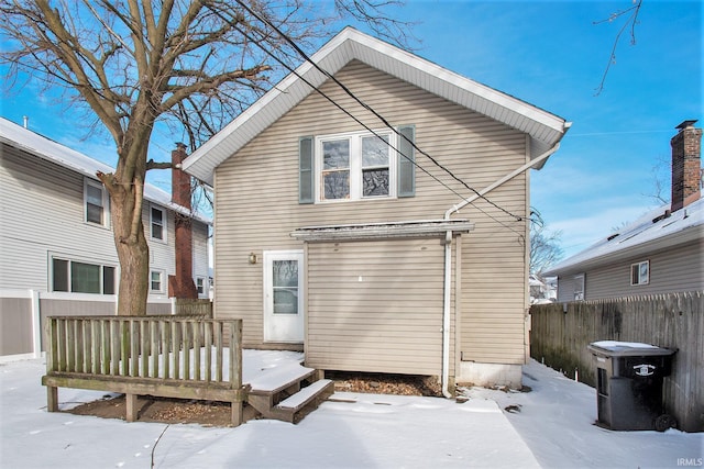 snow covered back of property with a deck