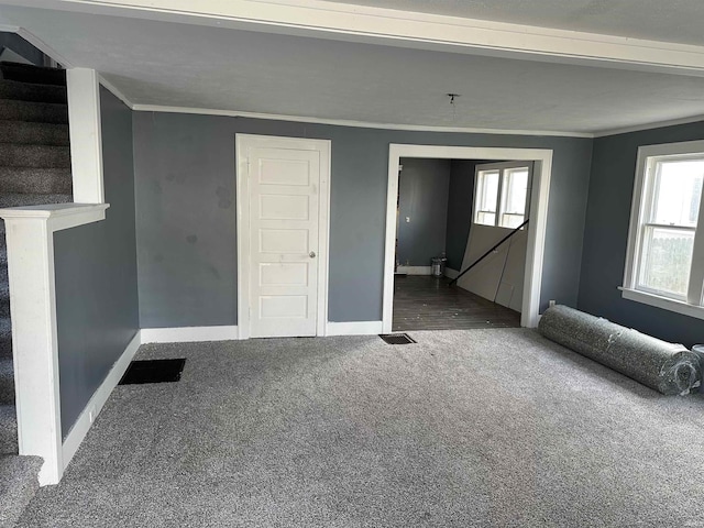 unfurnished living room with ornamental molding and carpet floors